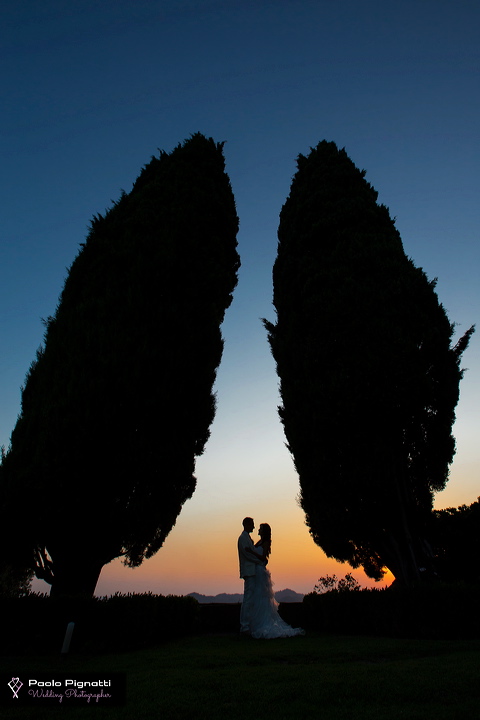 Sposi abbracciati al tramonto in mezzo a due cipressi